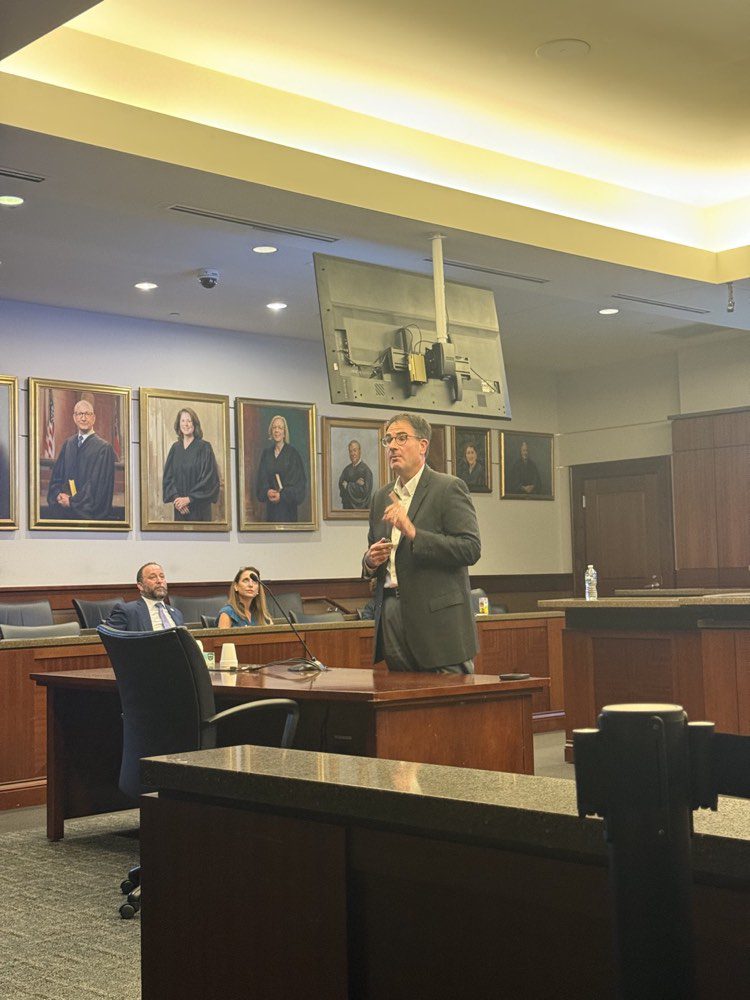 Speaker addressing Cobb 101 participants seated in a courtroom